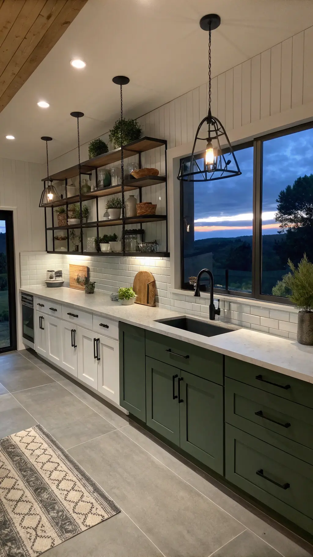 Twilight view of a modern farmhouse kitchen with white and olive-green two-tone cabinets, floating black metal shelves, concrete counters, and dramatic shadows from geometric pendant lights; showcasing a blend of contemporary and rustic styles.